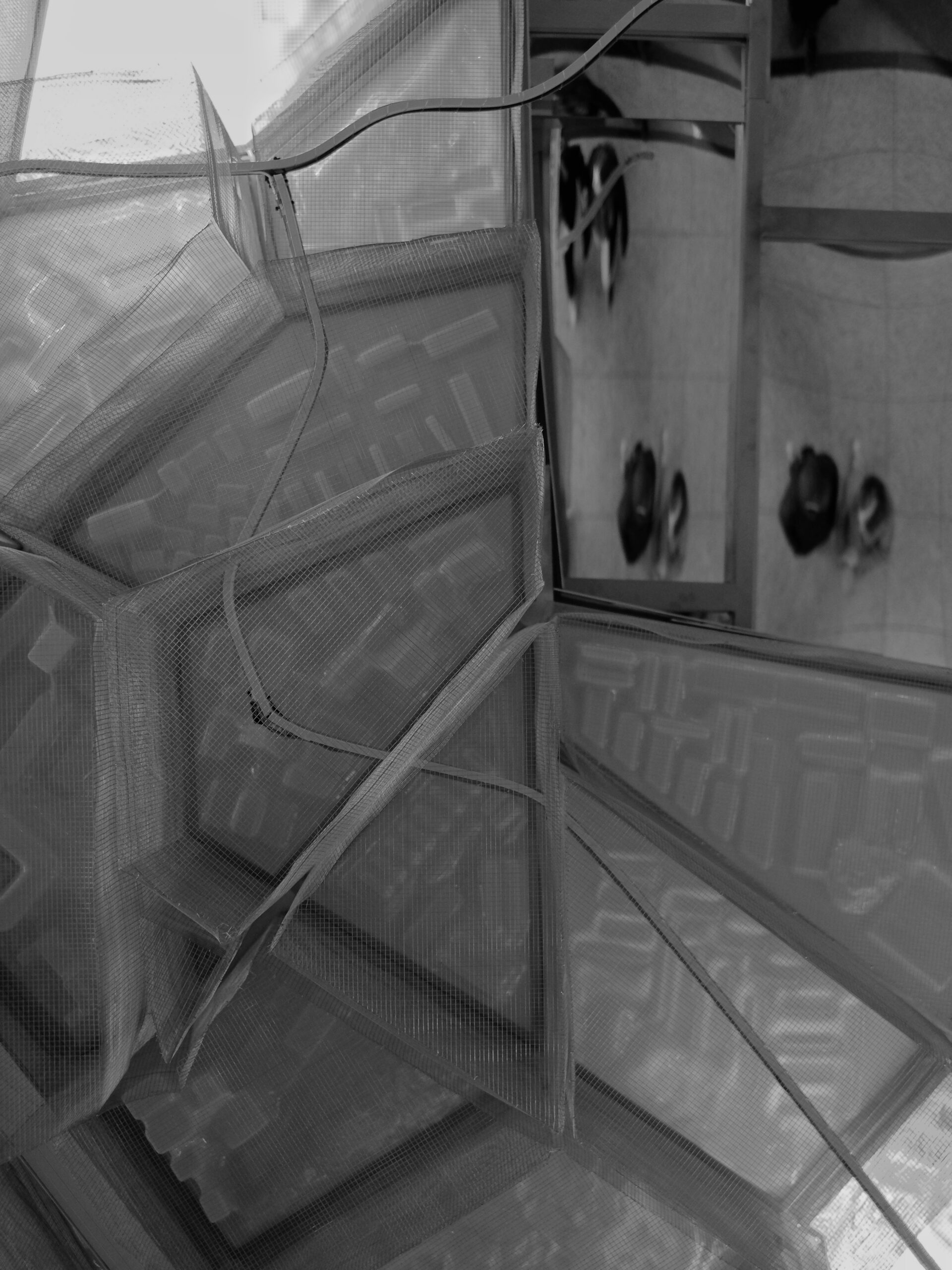 Grijze vlakken verdeeld, met in de vakken rechtsboven in de reflectie van mensen.