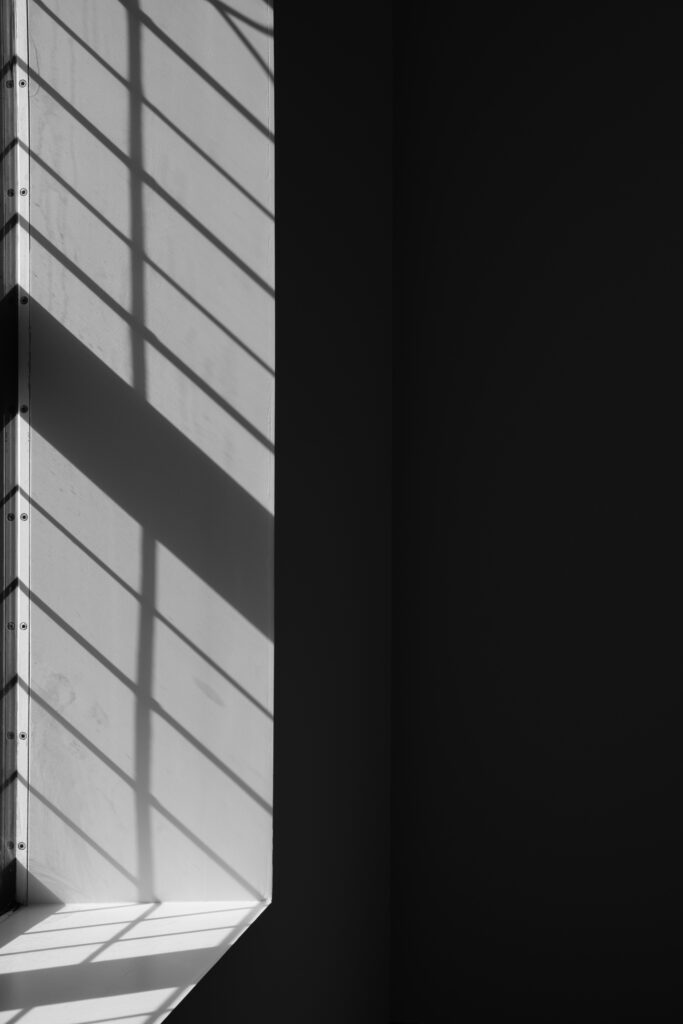 Rechts een zwart vlak, links een heel licht grijs vlak met donkerdere grijze schuine strepen.