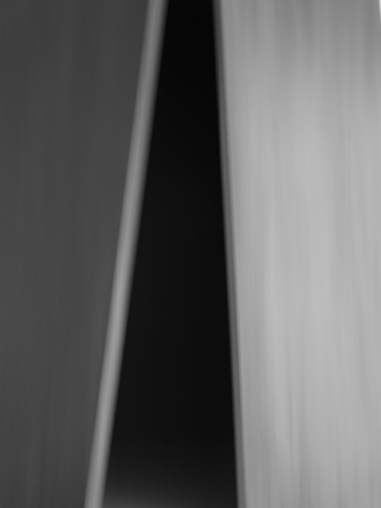 Zwarte driehoek in het midden, links een lichter vlak en rechts een nog lichter vlak.